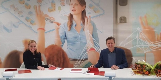 Een man en een vrouw tekenen een overeenkomst aan een tafel 