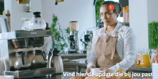 Vrouw werkt als barista en houdt een kopje koffie in haar hand. Tekst 'vind de update die bij jou past'